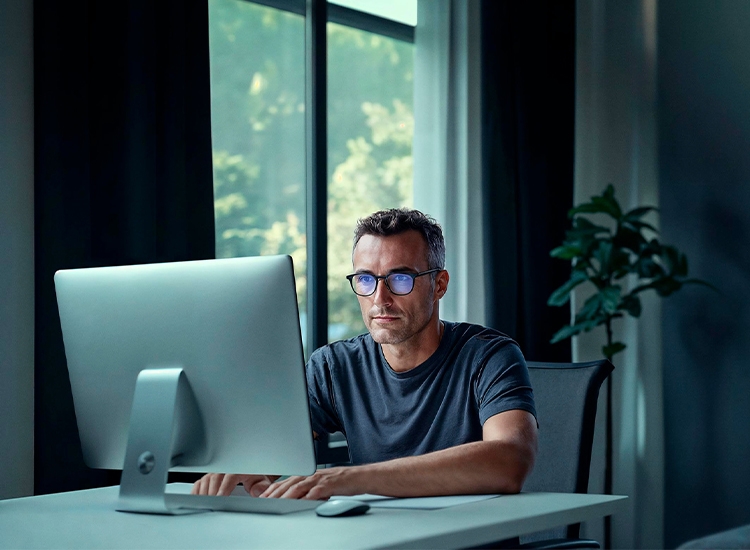 Mann trägt Nahkomfortbrille und arbeitet am PC